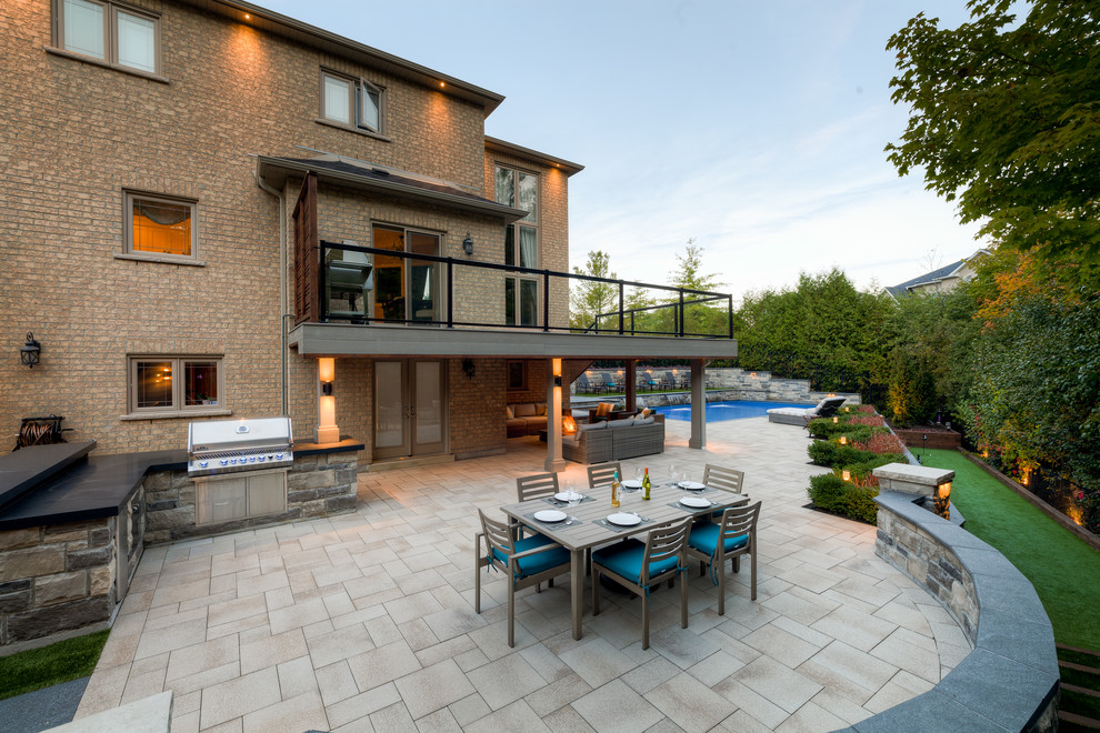 This is an example of a large contemporary back patio in Toronto with a fire feature and concrete paving.