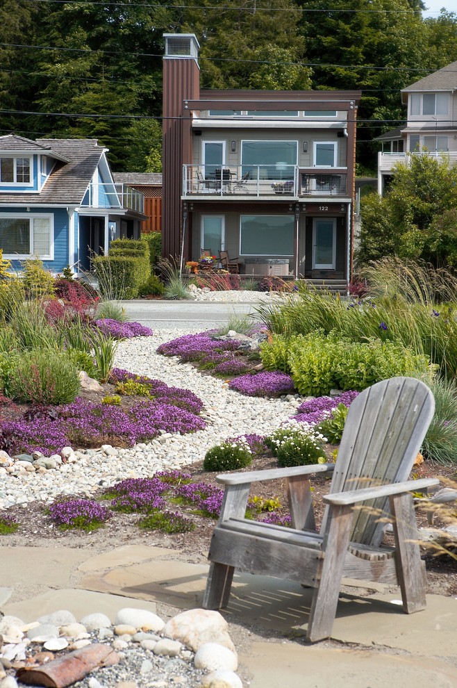 На фото: солнечный участок и сад на переднем дворе в морском стиле с хорошей освещенностью, покрытием из гравия и клумбами