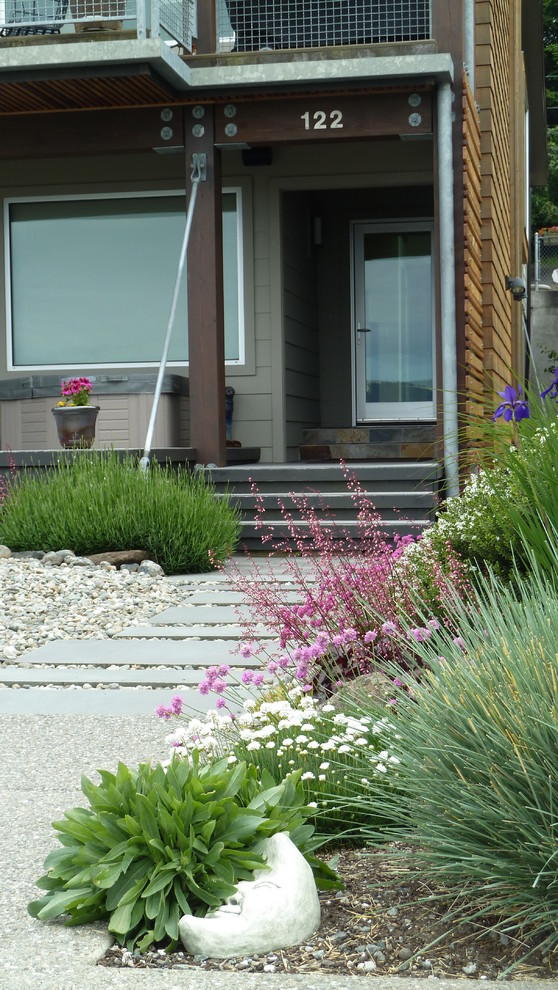 Small contemporary back full sun garden for summer in Seattle with a garden path and natural stone paving.