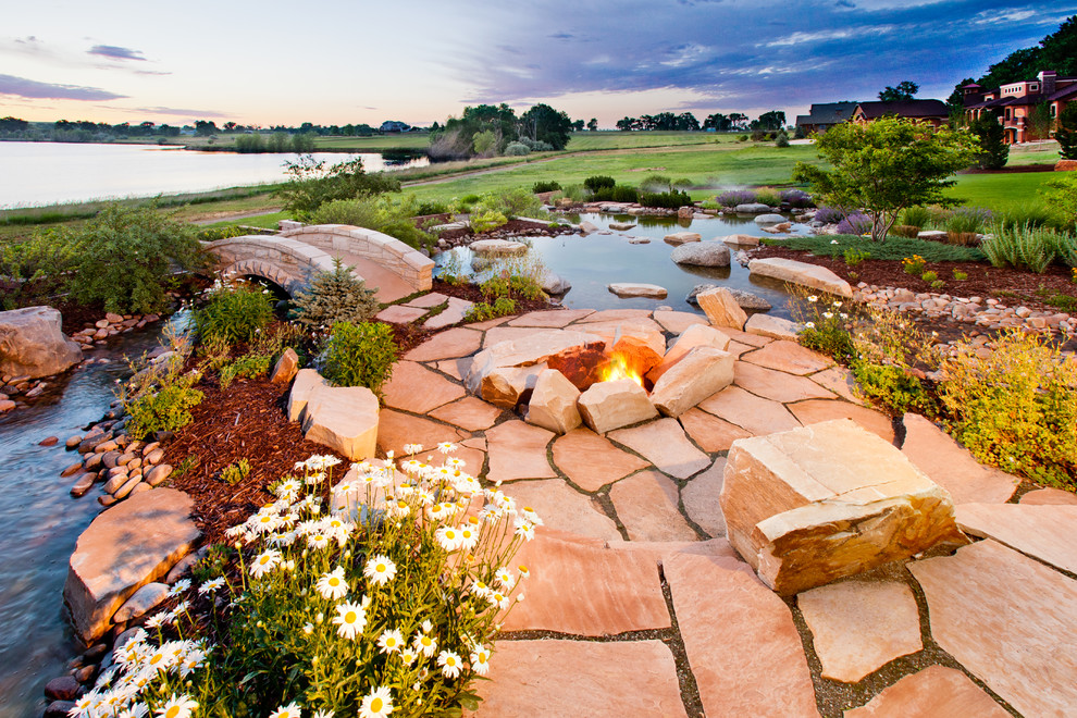 Large traditional back formal full sun garden in Denver with a fire feature and natural stone paving.