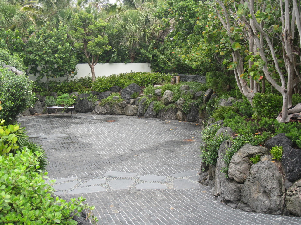 Inspiration för mellanstora asiatiska uppfarter framför huset, med naturstensplattor och en stödmur