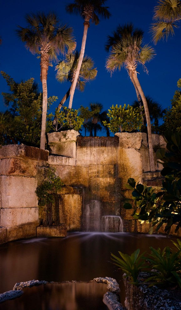 Immagine di un ampio giardino tropicale esposto a mezz'ombra dietro casa in estate con fontane e pavimentazioni in pietra naturale