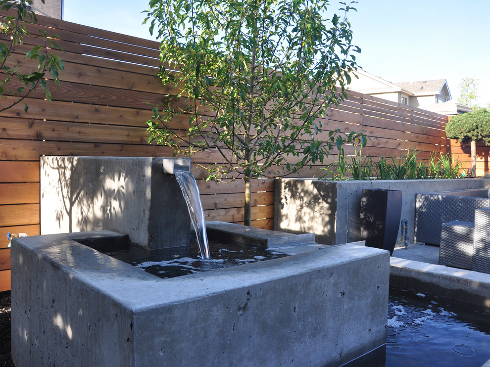 Inspiration for a large modern backyard concrete paver water fountain landscape in Vancouver.