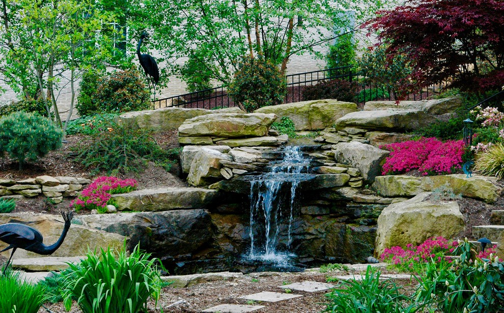 На фото: солнечный, весенний садовый фонтан среднего размера на склоне в стиле рустика с хорошей освещенностью и покрытием из каменной брусчатки