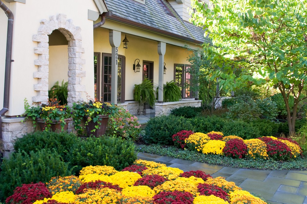 Inspiration för en vintage trädgård framför huset och blomsterrabatt, med naturstensplattor