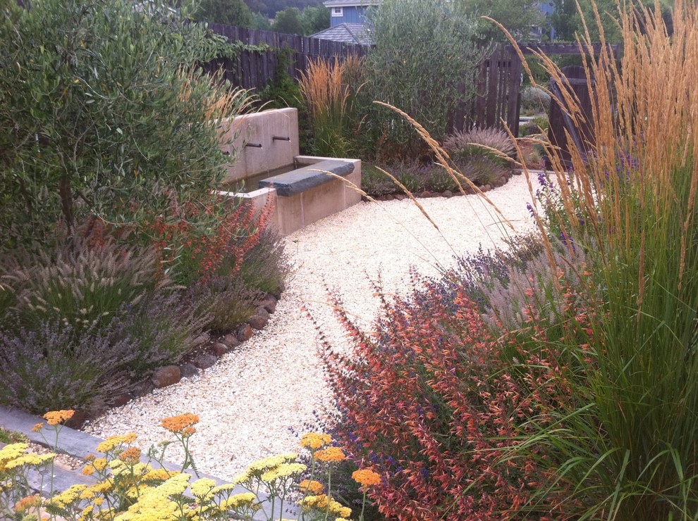 Modelo de jardín clásico de tamaño medio en primavera en patio trasero con exposición parcial al sol, jardín francés, fuente y gravilla