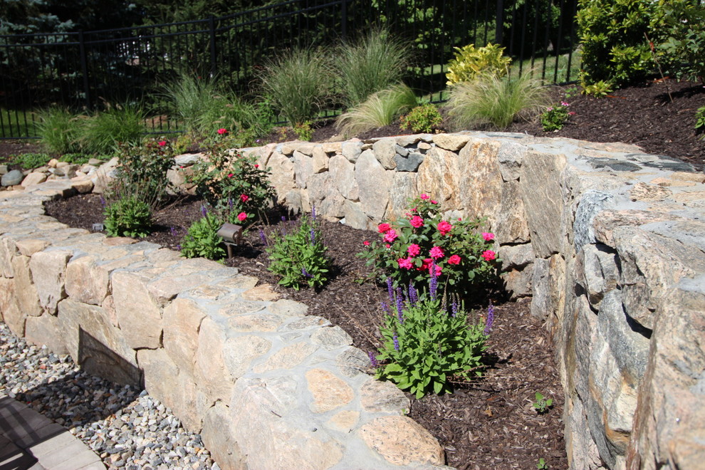 Design ideas for a large classic back xeriscape full sun garden for spring in New York with a retaining wall and concrete paving.