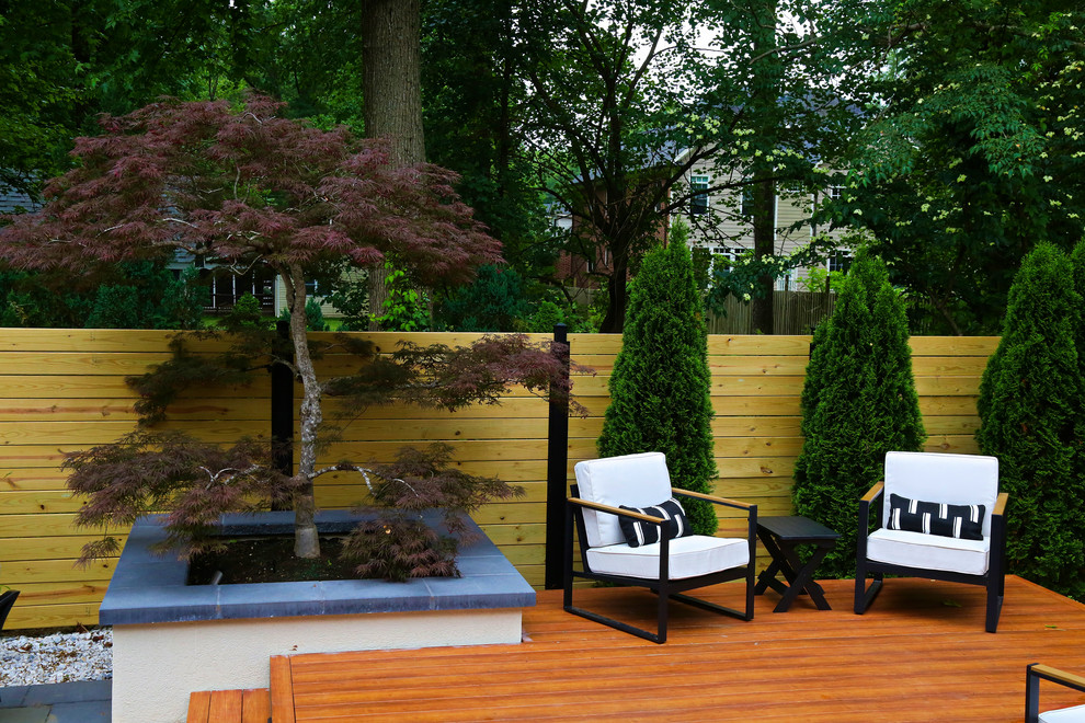 This is an example of a large contemporary privacy and partial sun backyard formal garden in DC Metro with decking.
