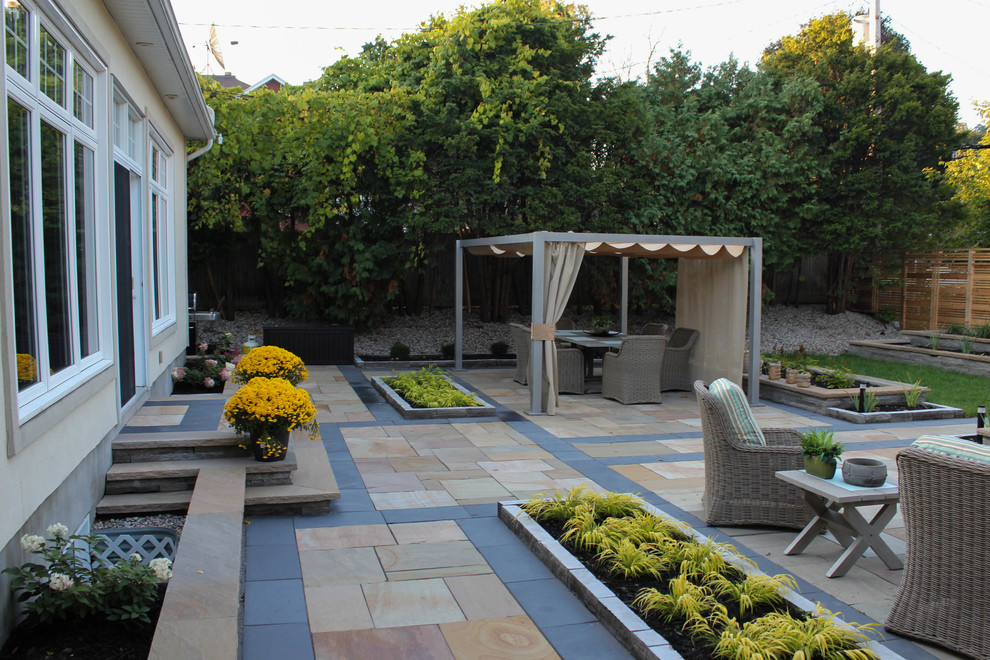 Immagine di un grande orto in giardino moderno esposto in pieno sole dietro casa con pavimentazioni in pietra naturale
