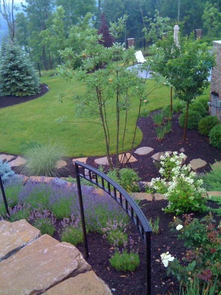 This is an example of a mid-sized transitional full sun backyard stone landscaping in Cincinnati for spring.