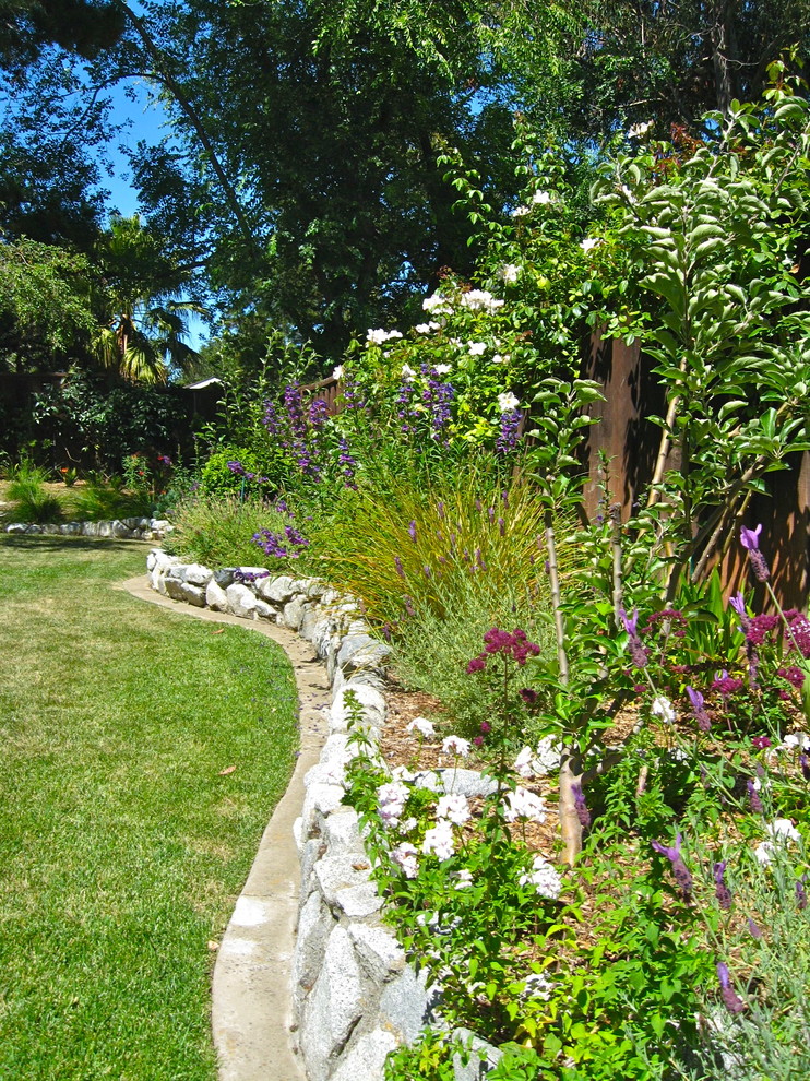 Idee per un grande giardino chic esposto a mezz'ombra dietro casa con un muro di contenimento