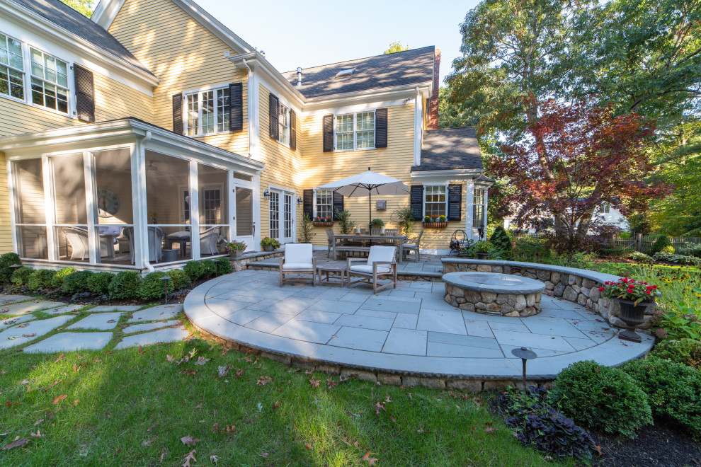 Inspiration for a mid-sized traditional partial sun backyard stone landscaping in Boston with a fire pit.