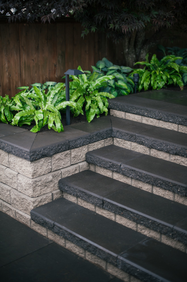 This is an example of a modern partial sun backyard concrete paver landscaping in Vancouver.