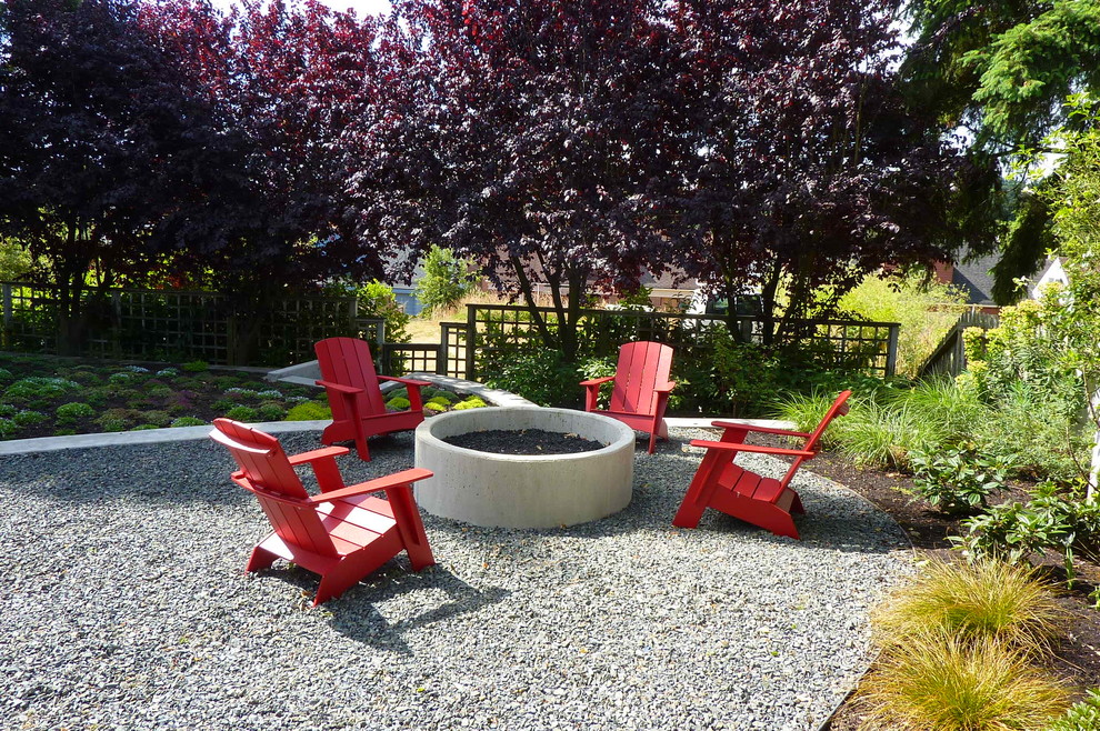 Ejemplo de jardín actual de tamaño medio en verano en patio trasero con brasero, exposición parcial al sol y gravilla