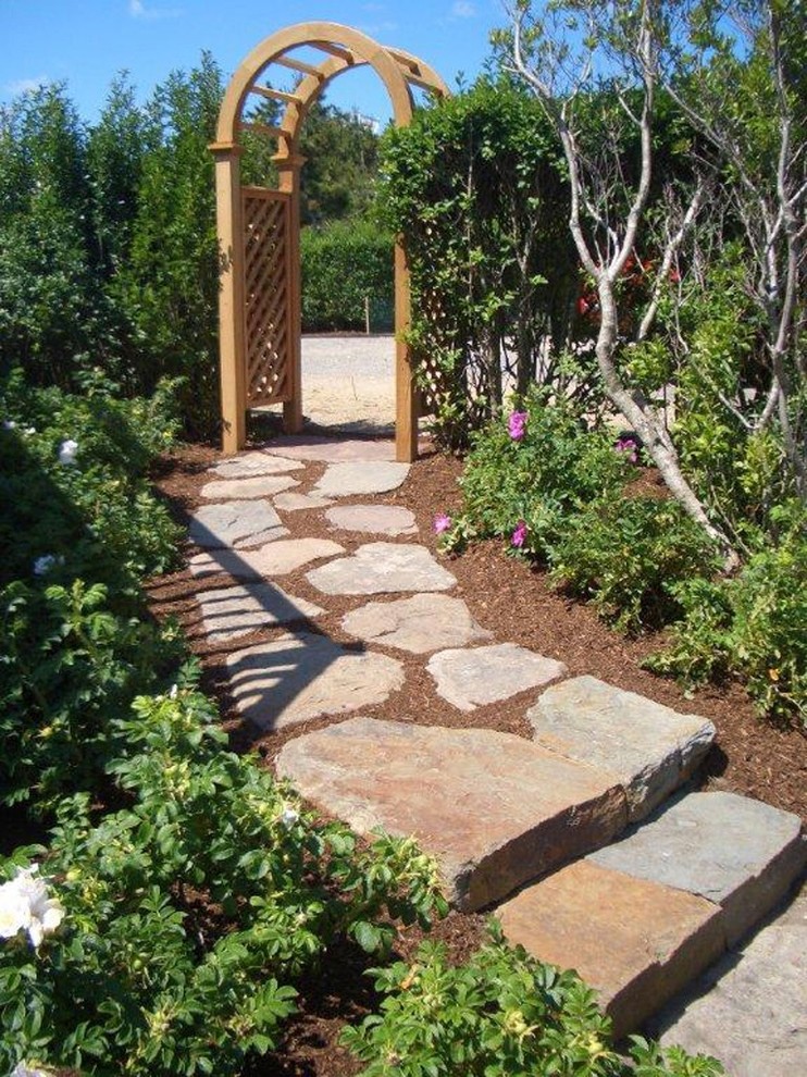 Inspiration för klassiska trädgårdar framför huset, med en trädgårdsgång och naturstensplattor