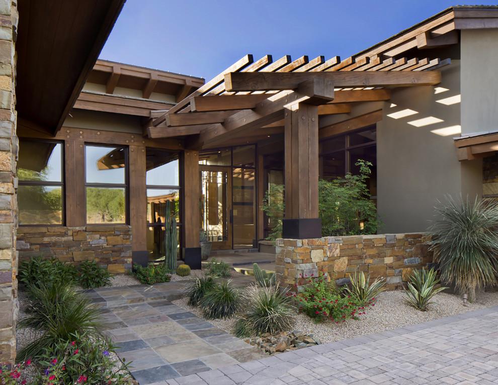 This is an example of a large classic front xeriscape garden in Phoenix with a garden path and natural stone paving.