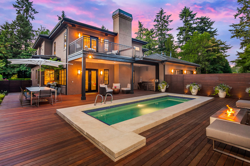 This is an example of a large contemporary partial sun backyard water fountain landscape in Seattle with decking for summer.