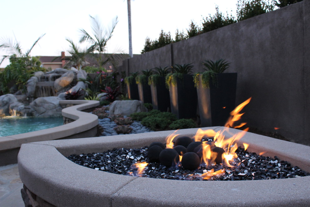 Design ideas for a medium sized contemporary back xeriscape partial sun garden for summer in Orange County with a fire feature and natural stone paving.