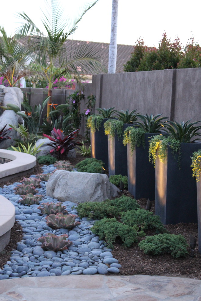 Imagen de jardín de secano contemporáneo de tamaño medio en verano en patio trasero con fuente, exposición parcial al sol y adoquines de piedra natural