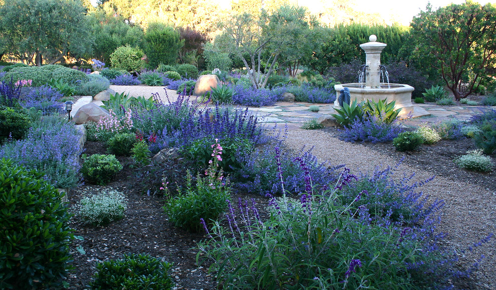 Modelo de jardín de secano mediterráneo extra grande en verano en patio trasero con fuente, exposición total al sol y gravilla
