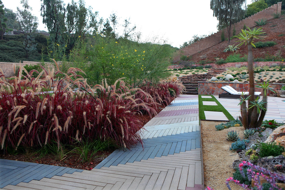 Пример оригинального дизайна: большой солнечный регулярный сад на заднем дворе в современном стиле с хорошей освещенностью, настилом и подпорной стенкой