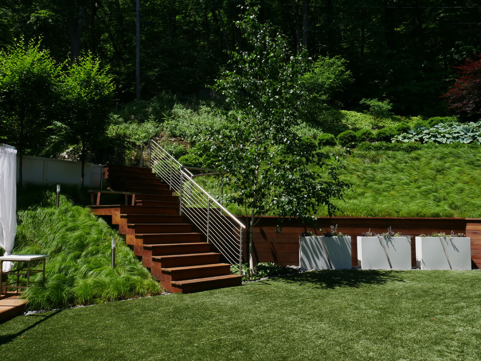 Diseño de jardín contemporáneo de tamaño medio en ladera con muro de contención y exposición parcial al sol
