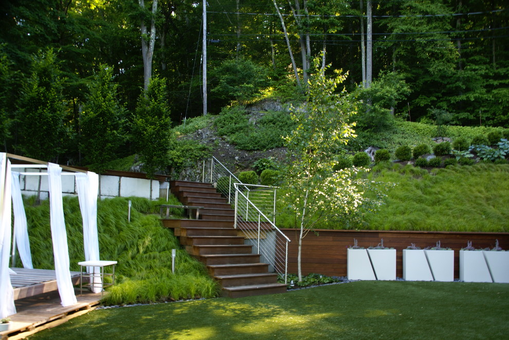 Medium sized contemporary sloped partial sun garden in New York with a retaining wall.