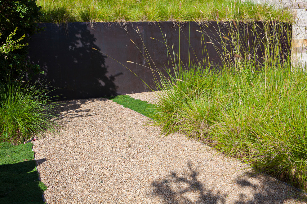 Réalisation d'un très grand jardin latéral minimaliste l'automne avec une exposition ensoleillée et du gravier.