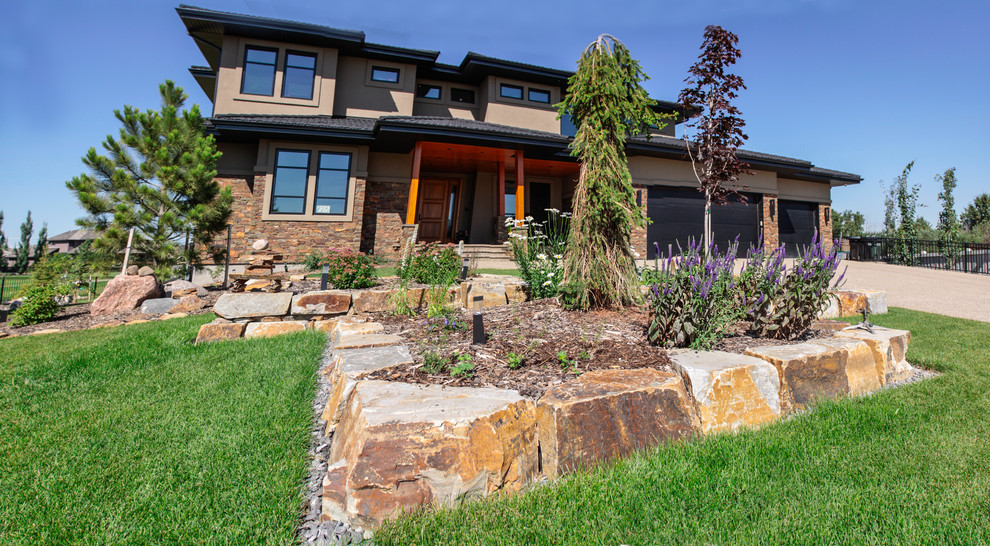This is an example of a large contemporary front garden in Edmonton with natural stone paving.