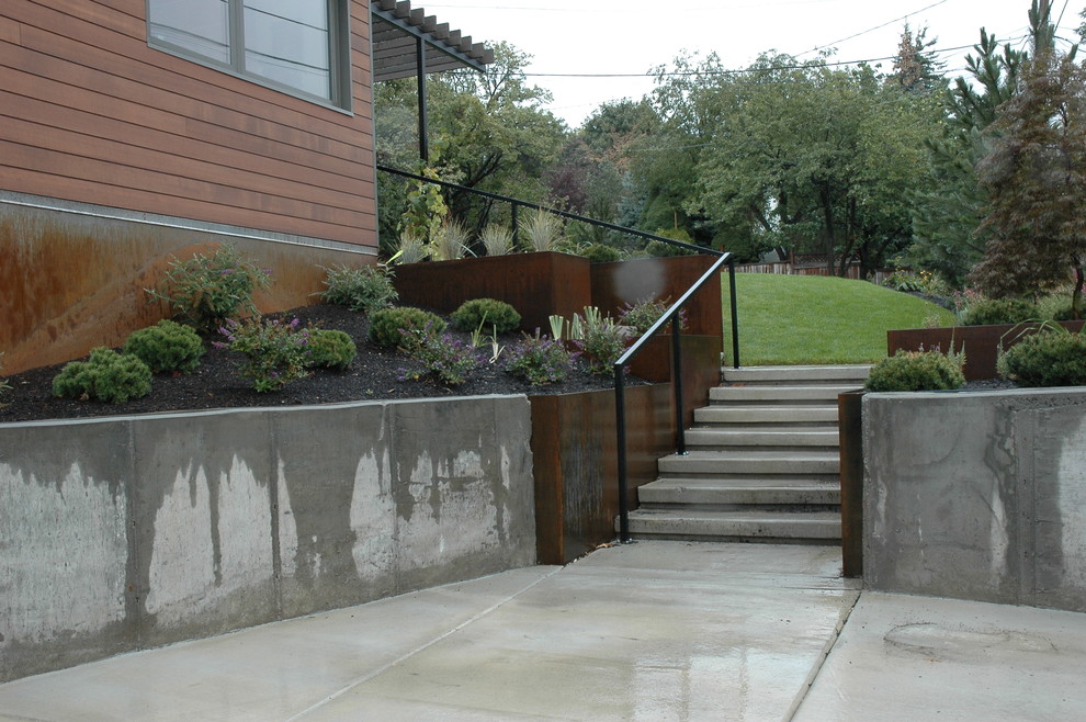 Inspiration for a large modern front xeriscape full sun garden for summer in Salt Lake City with a retaining wall and concrete paving.