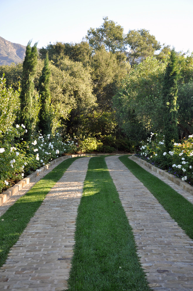 Design ideas for an expansive mediterranean front driveway garden in Santa Barbara with brick paving.
