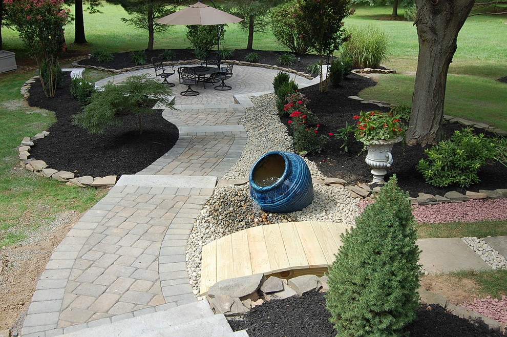 This is an example of a mid-sized contemporary partial sun backyard brick landscaping in Newark for spring.