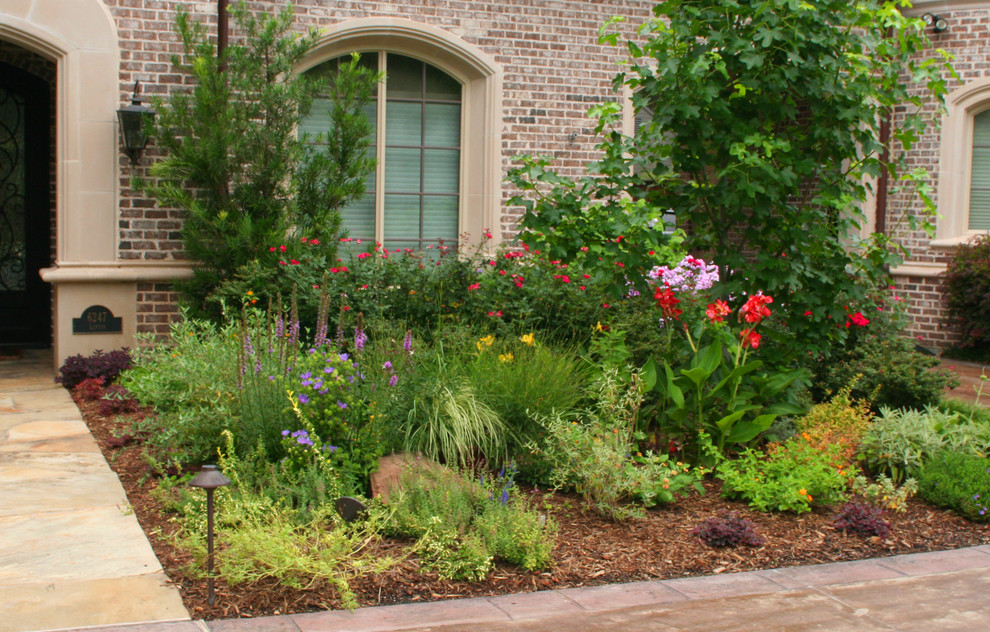 Ejemplo de jardín clásico grande en verano en patio delantero con jardín francés, exposición total al sol y adoquines de ladrillo
