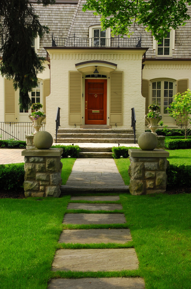 This is an example of a large traditional partial sun front yard stone formal garden in Toronto for spring.