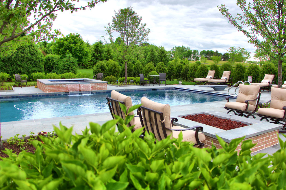 Ejemplo de piscina clásica de tamaño medio en patio trasero con adoquines de piedra natural