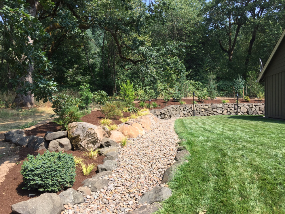 Photo of a mid-sized traditional full sun backyard gravel retaining wall landscape in Portland.