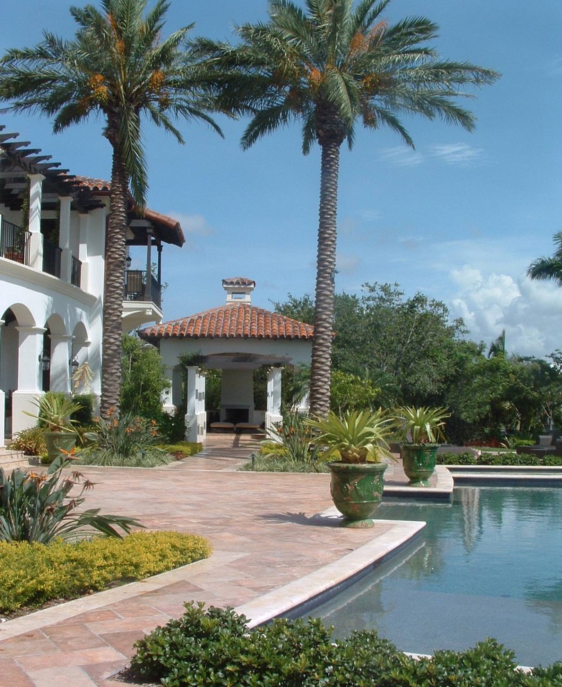 Photo of a mediterranean back garden in Miami with a potted garden and natural stone paving.