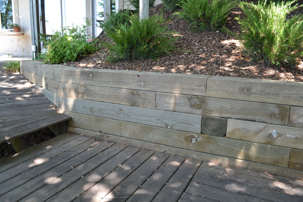 Diseño de jardín rústico de tamaño medio en patio trasero con muro de contención y adoquines de piedra natural
