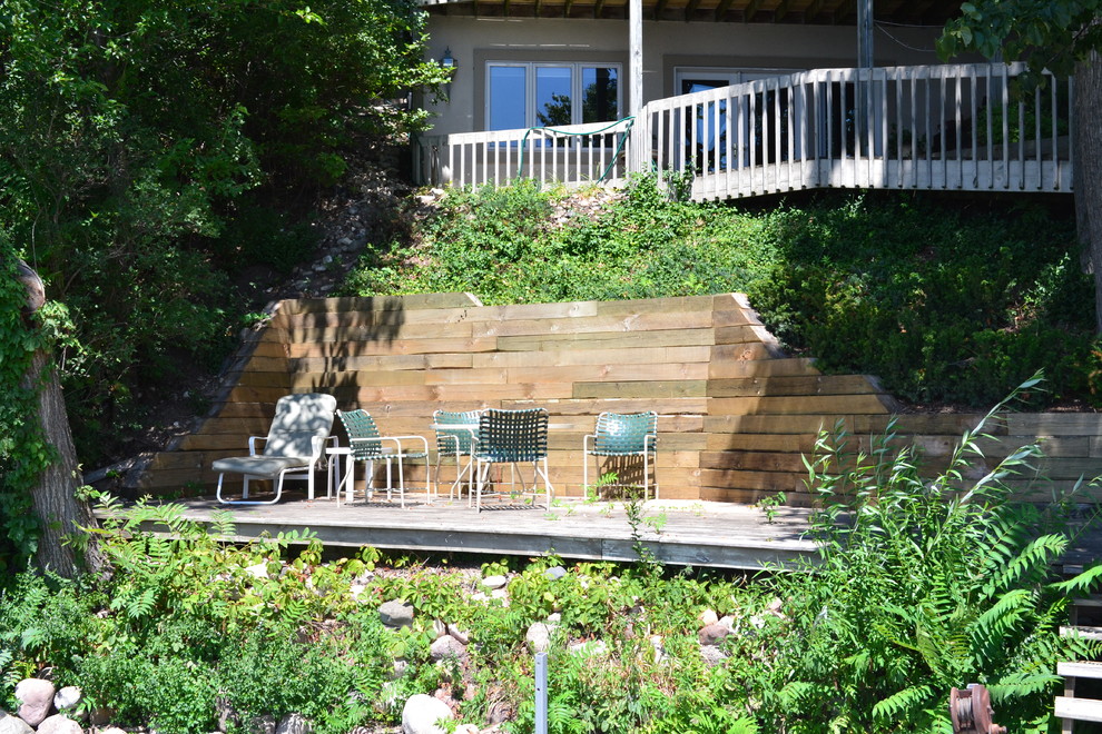 Design ideas for a mid-sized rustic backyard stone retaining wall landscape in Milwaukee.