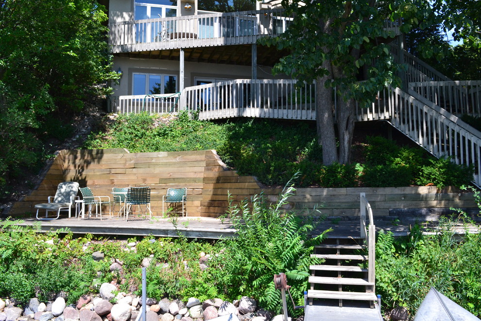 This is an example of a mid-sized rustic backyard stone retaining wall landscape in Milwaukee.