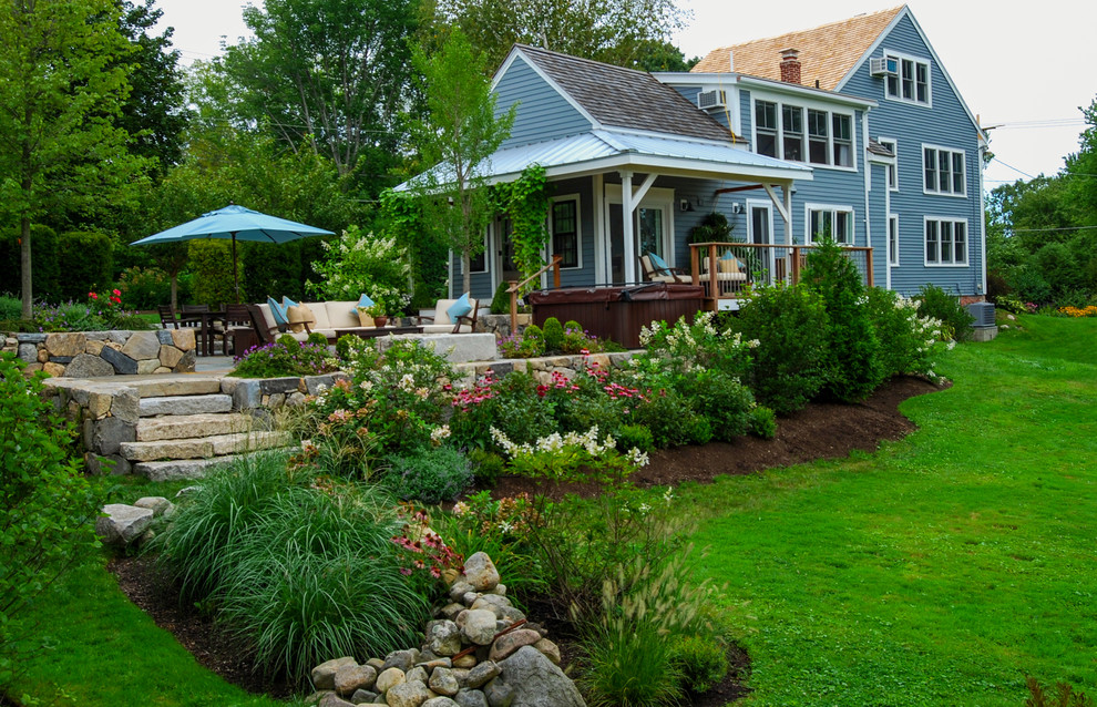 This is an example of a mid-sized farmhouse full sun backyard stone landscaping in Boston.