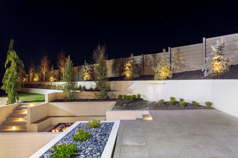 Стильный дизайн: огромный участок и сад на заднем дворе в современном стиле с местом для костра и мощением тротуарной плиткой - последний тренд