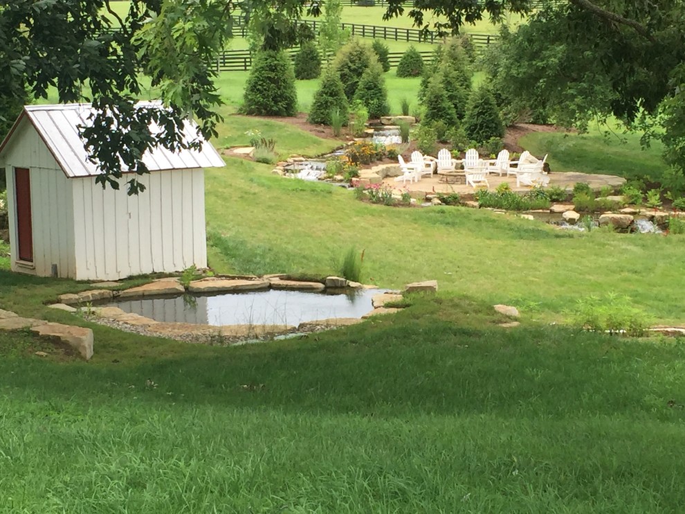 Photo of a medium sized rustic back partial sun garden in Other with a pond and mulch.