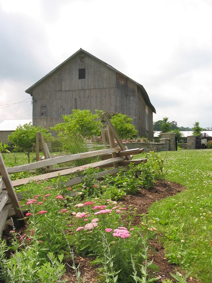 Esempio di un ampio giardino country esposto in pieno sole dietro casa in primavera con pacciame e un ingresso o sentiero