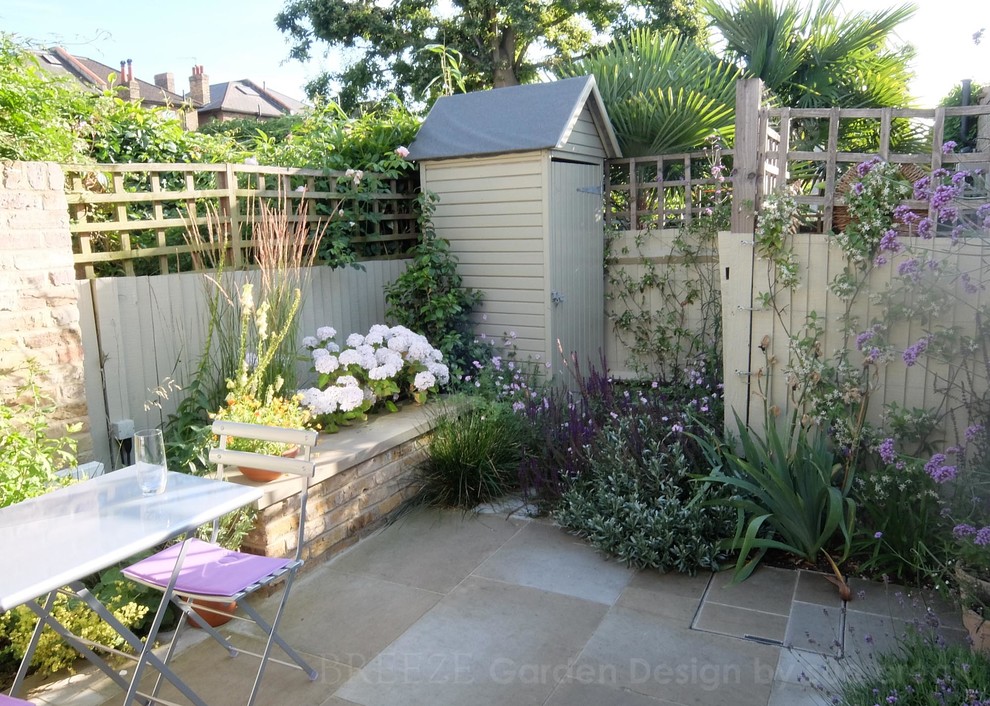 Design ideas for a small farmhouse courtyard garden in London with natural stone paving.