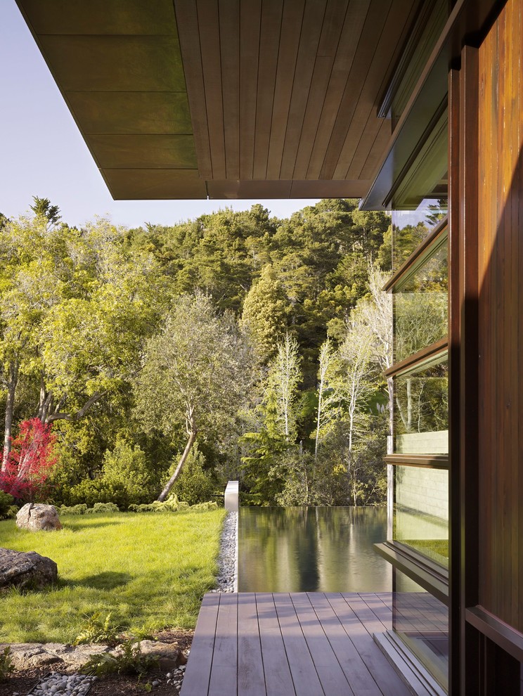 Cette image montre un grand jardin minimaliste avec un point d'eau et une terrasse en bois.