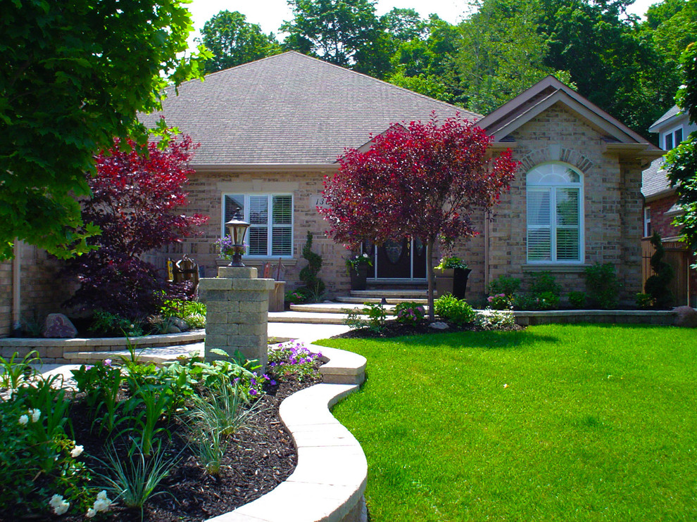 This is an example of a large traditional front formal full sun garden in Toronto with a garden path and concrete paving.