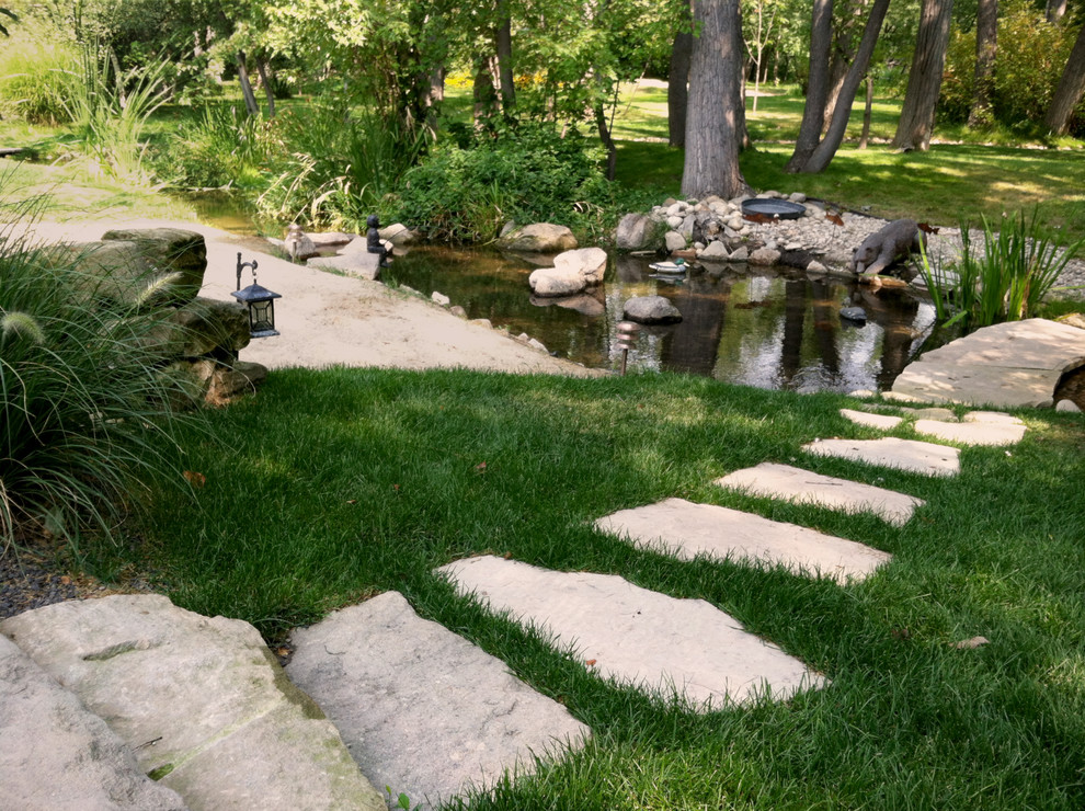 This is an example of a large rustic partial sun backyard stone landscaping in Boise.