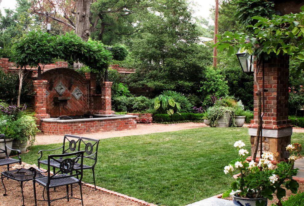 Ejemplo de jardín clásico grande en patio trasero con fuente y adoquines de ladrillo