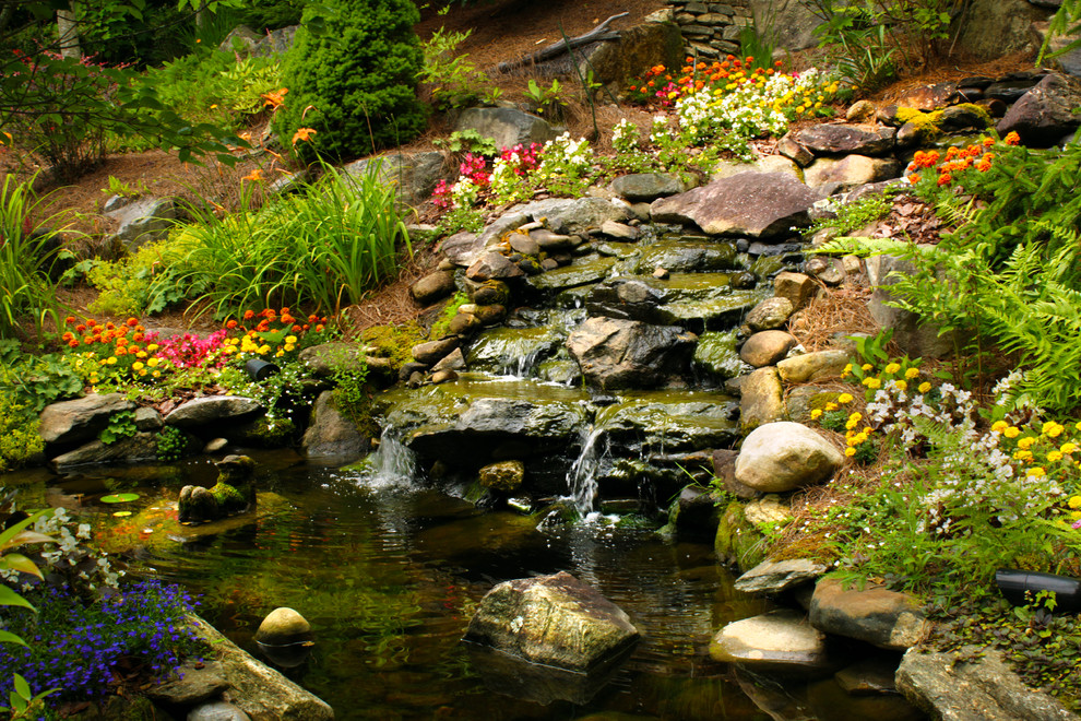 Ispirazione per un laghetto da giardino tradizionale esposto a mezz'ombra di medie dimensioni in estate con un pendio, una collina o una riva e pacciame